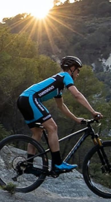Personne faisant du VTT sur un sentier rocheux au lever du soleil.