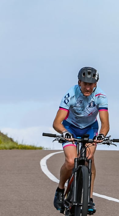 Radfahrer auf einer Landstraße unter einem Regenbogen