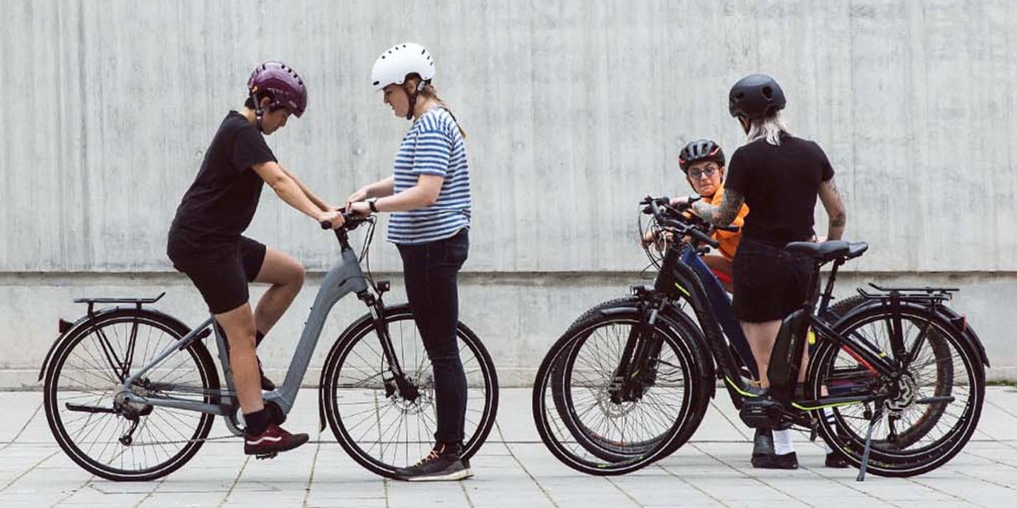 Group of people with bicycles standing and talking near a concrete wall