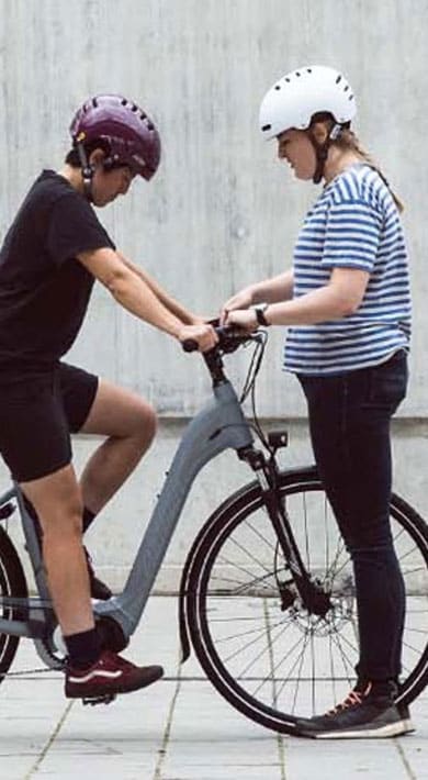 Group of people with bicycles standing and talking near a concrete wall