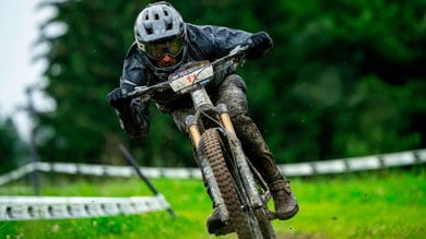 Cyclist in helmet riding downhill on a muddy trail