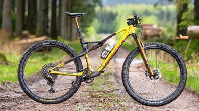 Gele mountainbike op een bospad.