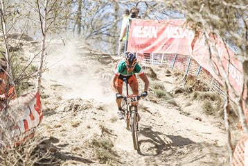 Mountainbiker racet over een stoffig pad tijdens een wedstrijd.