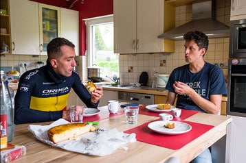 Twee mannen eten aan een keukentafel.