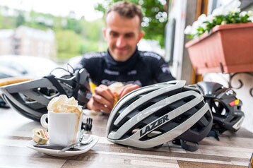 Fietser met helmen en koffie op een tafel.