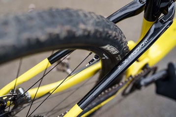 Close-up van een geel-zwart fietsframe en achterband.
