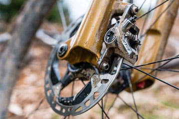 Close-up van een mountainbikeschijfrem met modder.