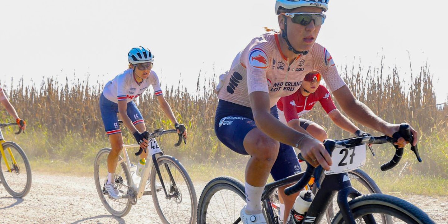 Ciclistas em uma trilha rural de terra com milharais ao fundo