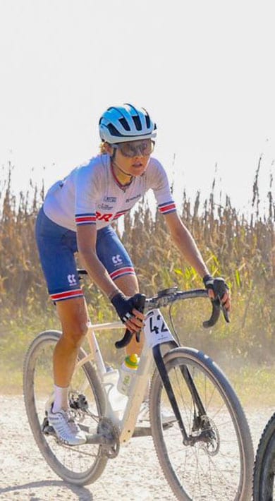 Ciclistas em uma trilha rural de terra com milharais ao fundo