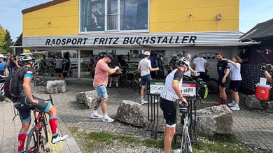 Radfahrer versammeln sich an einem sonnigen Tag vor einem Fahrradgeschäft.