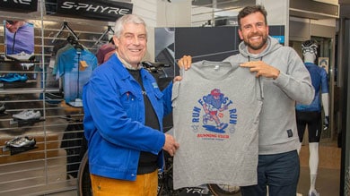 Zwei Männer halten ein graues Laufclub-T-Shirt in einem Sportgeschäft.
