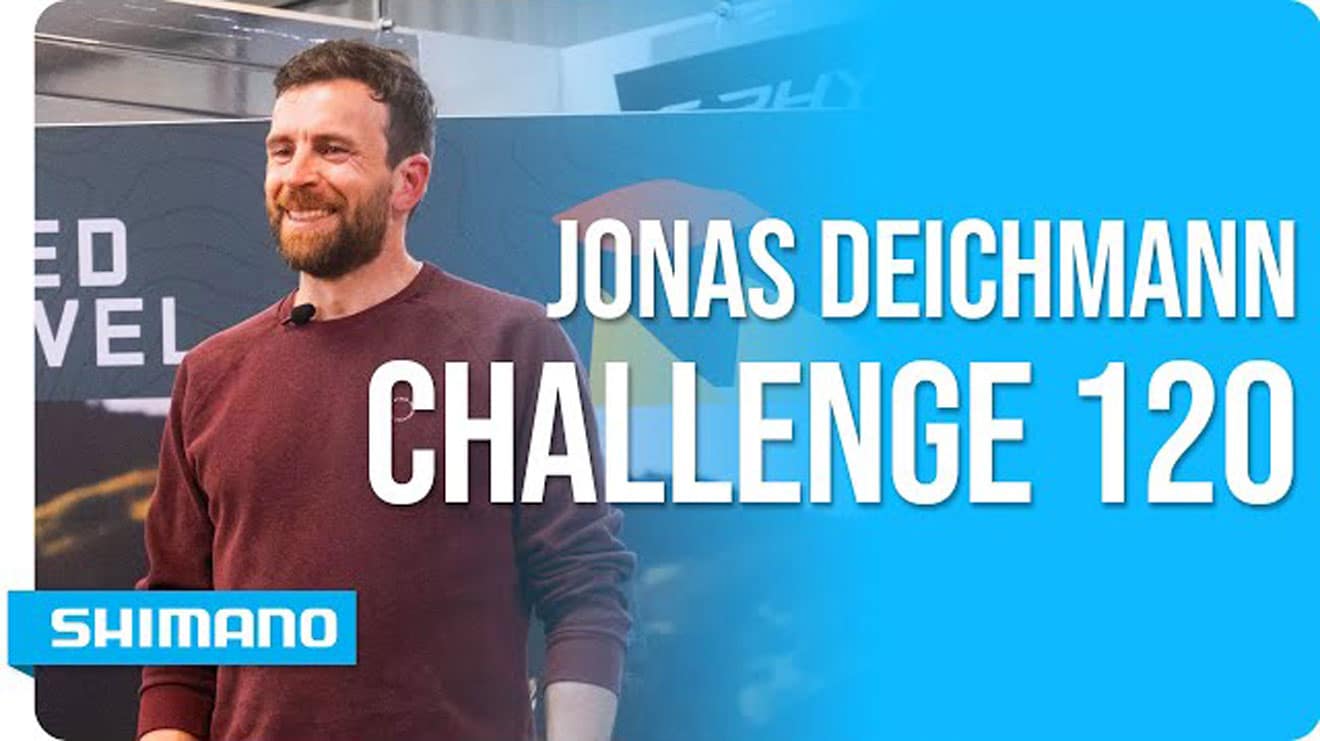 Mann im weinroten Shirt mit dem Text 'Jonas Deichmann Challenge 120' und dem 'Shimano'-Logo.