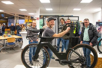 Gruppe bewundert ein Scott-Rennrad in einem Ausstellungsraum.