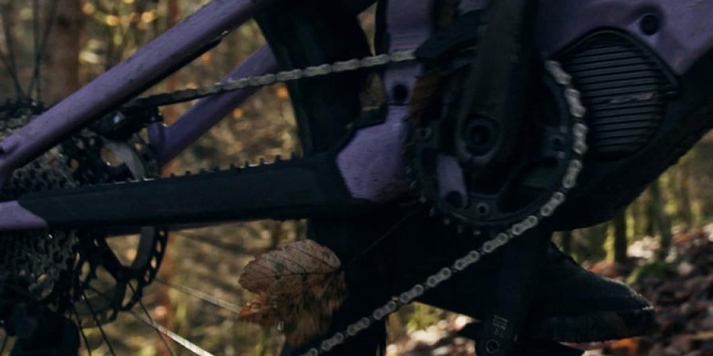 Close-up of a mountain bike's rear wheel and drivetrain on a forest trail