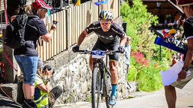 Radfahrer bei einem Rennen, während Zuschauer Fotos machen und jubeln