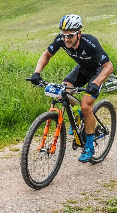Radfahrer fährt auf einem Feldweg durch üppig grüne Wiesen