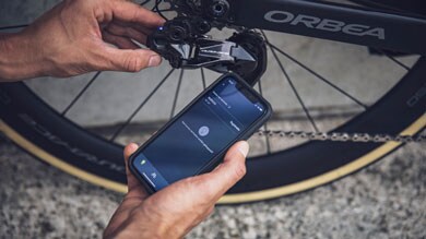 Persona ajusta el desviador de la bicicleta usando una app en su smartphone.