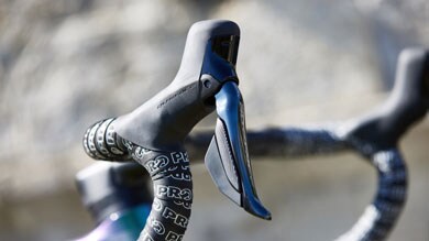 Primer plano de un mando de cambios de bicicleta y cinta del manillar.