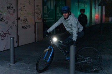 Fietser rijdt 's nachts in een stedelijk gebied langs muren met graffiti.