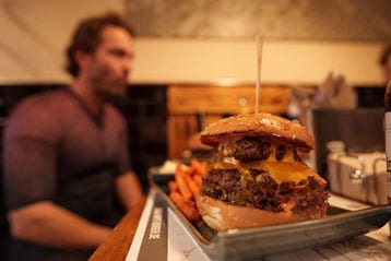 Close-up van een dubbele cheeseburger met zoete aardappelfriet in een restaurant.