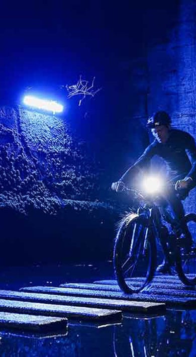 Fietser rijdt in een blauw verlichte tunnel in de schemering.