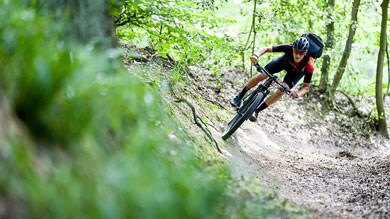 Mountainbiker op een bospad, rijdt door een bocht.