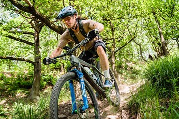 Mountainbiker rijdt op een zonnige dag over een bospad.
