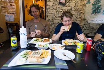 Twee personen genieten van een maaltijd met drankjes aan een restauranttafel.