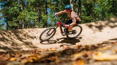 Mountainbiker maakt een bocht op een onverhard bospad.
