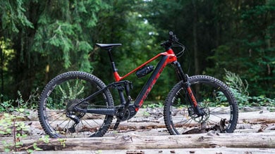 Rode mountainbike op bospad met boomstammen.