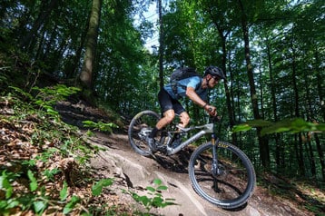 Fietser rijdt bergafwaarts op een bospad.