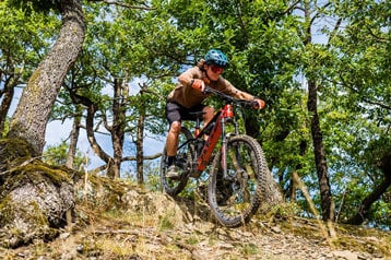 Mountainbiker rijdt een rotsachtig pad af in het bos.
