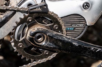 Close-up van een fietstrapas met zichtbare ketting en motor.