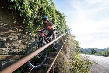 Persoon rijdt met een mountainbike een smalle buitentrap af.