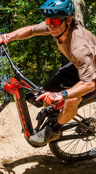 Mountainbiker maakt een bocht op een onverhard bospad.