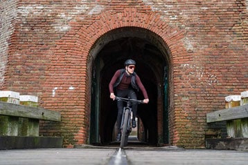 Fietser rijdt door een bakstenen boog.