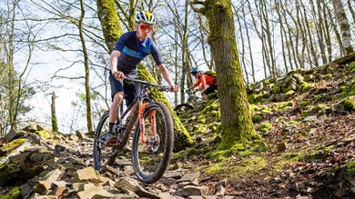 Fietsers mountainbiken op een rotsachtig bospad.