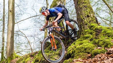 Mountainbiker navigeert een met mos bedekt bospad.