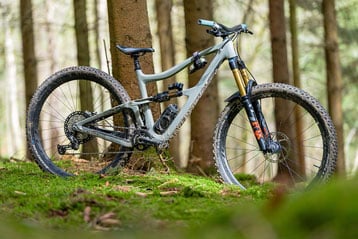 Mountainbike in een bosomgeving met bomen en groen gras.