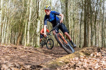 Twee fietsers mountainbiken op een bospad.