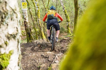 Mountainbiker navigeert een rotsachtig bospad.