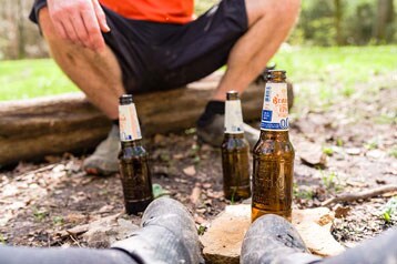 Twee mensen ontspannen buiten met drie bierflesjes op de grond.