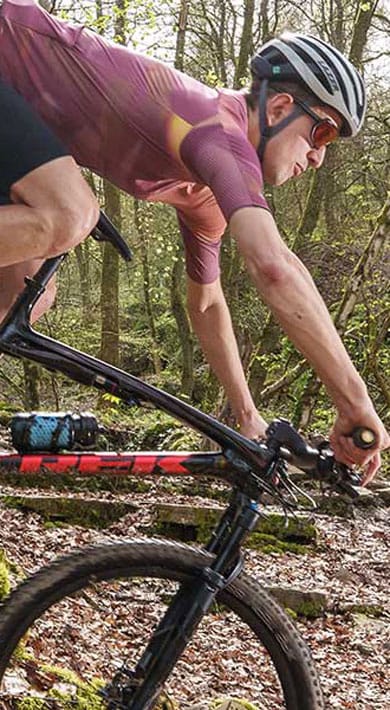 Fietser rijdt op een mountainbike over een bospad.