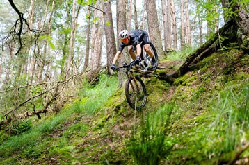 Mountainbiker daalt af op een steil bospad.