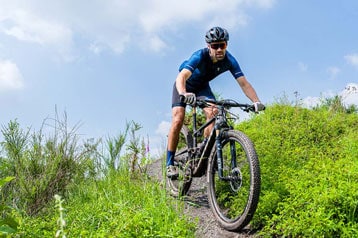 Fietser rijdt op een mountainbike over een grasachtig pad.