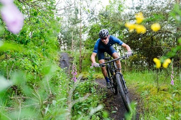 Mountainbiker rijdt over een bospad omringd door groen.