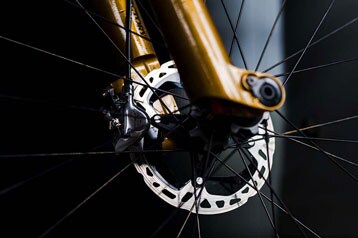Close-up van een fietsrem en spaken op een gele voorvork.