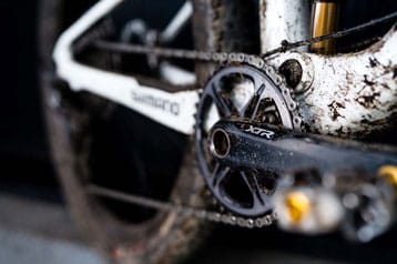 Close-up van een modderige fietsketting en tandwiel.