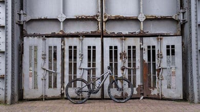 Fiets leunend tegen grote, verroeste metalen deuren.