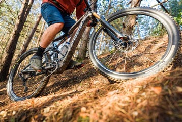 Persoon rijdt op een mountainbike over een bospad.